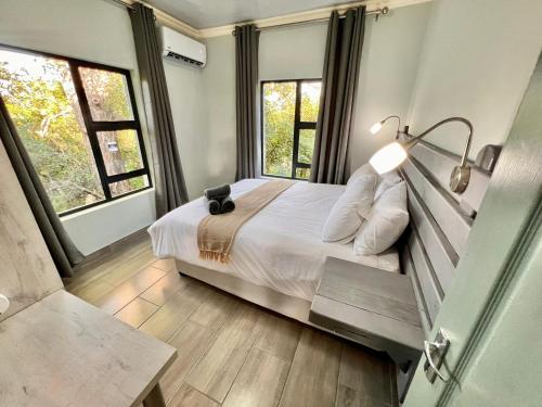 a bedroom with a bed with a lamp and two windows at Stories @ Marloth in Marloth Park