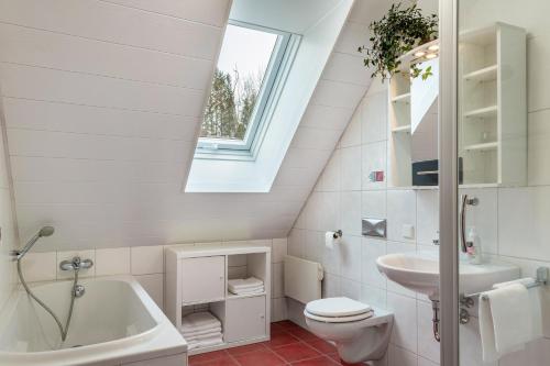 een badkamer met een wastafel, een toilet en een dakraam bij Ferienwohnung am Schlossberg in Odelzhausen