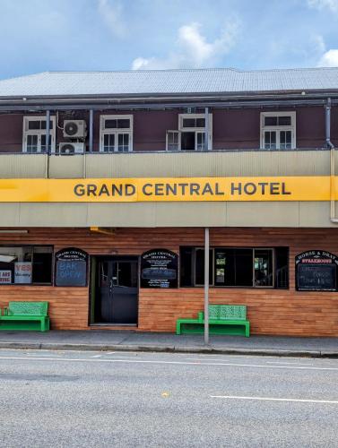 um grande hotel central com dois bancos verdes na frente em GRAND CENTRAL HOTEL PROSERPINE em Proserpine