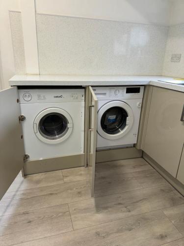 a laundry room with a washer and dryer under a counter at Cardiff Grangetown Stylish 3Bed House. in Cardiff