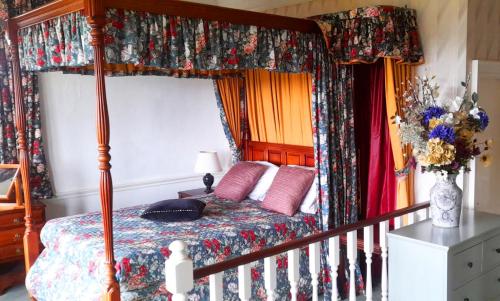 um quarto com uma cama de dossel e cortinas coloridas em The Falls - Value Rooms at Aultnagar Estate em Lairg