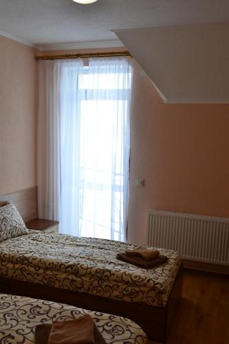 a bedroom with a bed and a window with white curtains at Hotel Restaurant Vizit in Truskavets