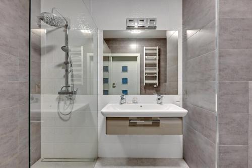 a bathroom with a sink and a shower with a mirror at Dom & House - Apartments Nowa Motława in Gdańsk
