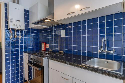a blue tiled kitchen with a sink and a stove at Mouraria Doll's House in Lisbon