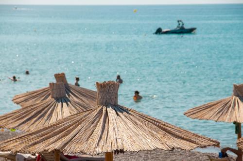 un gruppo di ombrelloni su una spiaggia con persone in acqua di Sun Beach Lindos a Lárdos