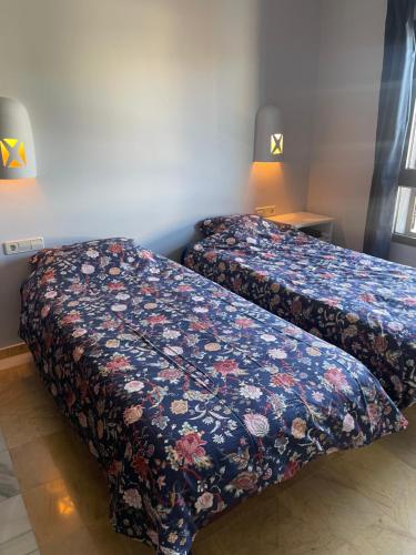 ein Schlafzimmer mit zwei Betten mit geblümter Tagesdecke in der Unterkunft Faro Park Villa Bella heated Pool in Playa Blanca