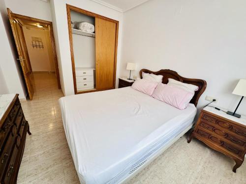 a bedroom with a bed with white sheets and pink pillows at A1040 - Terramar 1 - 2004 Finestrat in Villajoyosa