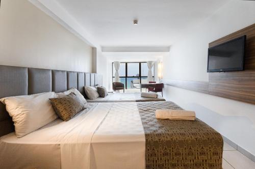 ein Schlafzimmer mit einem großen Bett und einem Flachbildfernseher in der Unterkunft Beach Class #1104 - Quádruplo por Carpediem in Recife