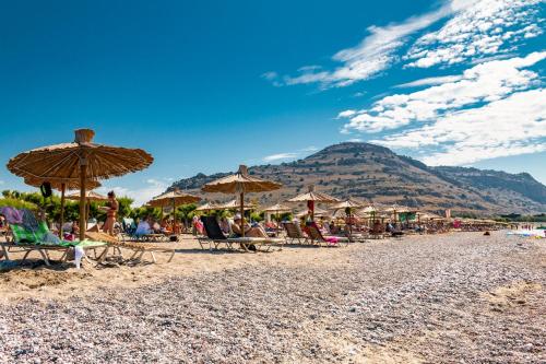un gruppo di sedie a sdraio e ombrelloni sulla spiaggia di Sun Beach Lindos a Lárdos