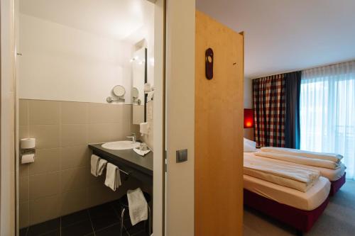 a bathroom with a bed and a sink in a room at Landhotel Gasthof Drexler GbR in Fürstenfeldbruck