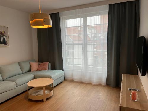 een woonkamer met een bank, een tafel en een raam bij Apartament na Starówce in Elblag