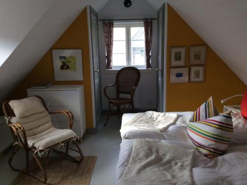 a bedroom with a bed and a chair and a window at Huset i gränden - granne med havet in Trelleborg
