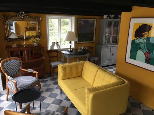 a living room with a yellow couch and chairs at Huset i gränden - granne med havet in Trelleborg