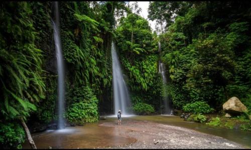 a person standing in front of a waterfall at Bujak Permai Villa Matahari Lombok NTB in Praya