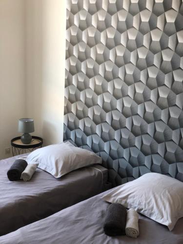 a bedroom with two beds and a geometric headboard at Votre oasis de détente : Appartement flambant neuf, 1 chambre, 4 couchages à Aubigné-racan in Aubigné-Racan