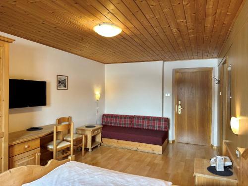 a room with a bed and a desk and a couch at Apparthotel Germania in Dobbiaco