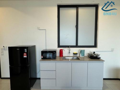 a kitchen with a sink and a black refrigerator at Urban Suites @ George Town Penang by BNB4U in George Town