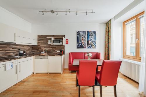 a kitchen and dining room with red chairs and a table at Serviced-Appartements-Josefstadt in Vienna