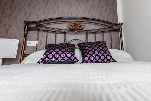 a bed with two purple pillows on top of it at Casa Rural Viña Vella in Esteiro