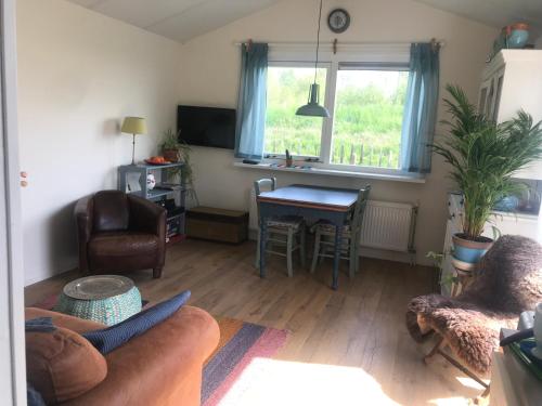 a living room with a couch and a table at Rosa's zonnige huisje bij duinen bos en strand in Warmenhuizen