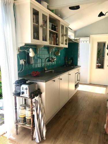 a kitchen with white cabinets and a sink at Rosa's zonnige huisje bij duinen bos en strand in Warmenhuizen