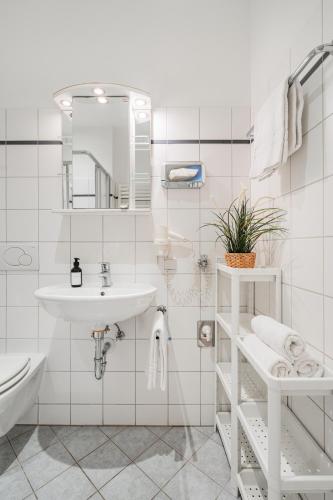 a white bathroom with a sink and a mirror at Serviced Apartments Josefstadt City in Vienna