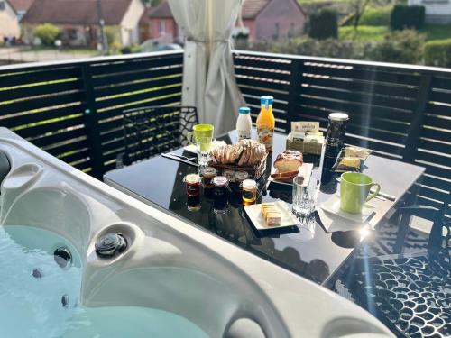 una mesa con comida y bebida y una bañera en Lodge spa privatif Starlette, séjour zen, en Meisenthal