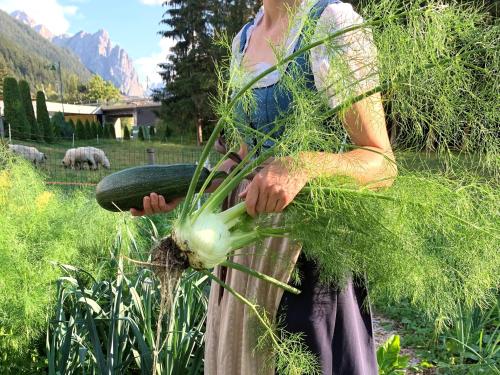 Una donna sta tenendo un mucchio di verdure di Apparthotel Germania a Dobbiaco