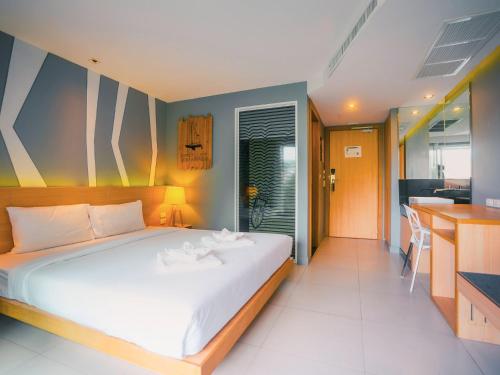 a bedroom with a large white bed and a kitchen at Mad Monkey Phuket in Patong Beach