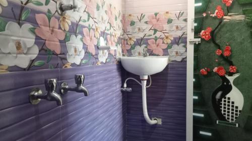 a bathroom with a sink and a wall with flowers at Aranmagan Paradise in Thiruchendur