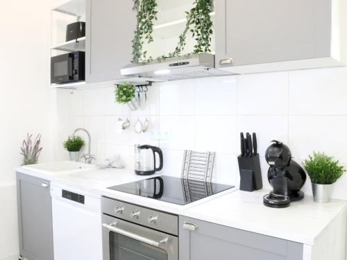 a white kitchen with white appliances and plants at Heimat Goslar Apartments "Zur Altstadt" in Goslar