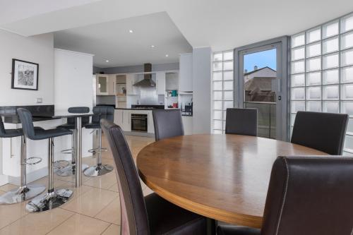 cocina y comedor con mesa de madera y sillas en 55 North Apartments Portrush, en Portrush