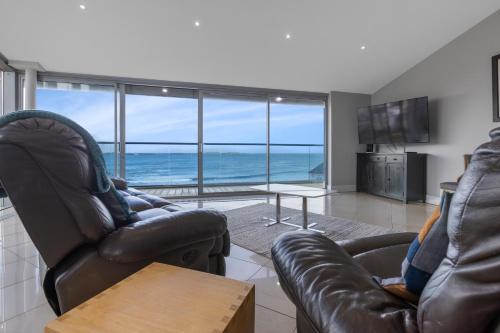 ein Wohnzimmer mit 2 Ledersesseln und Meerblick in der Unterkunft 55 North Apartments Portrush in Portrush