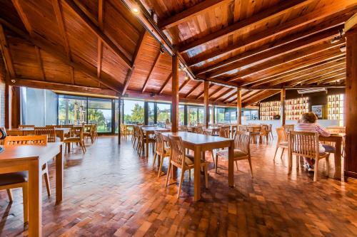 un comedor con mesas, sillas y ventanas en Portal del Lago Hotel en Villa Carlos Paz