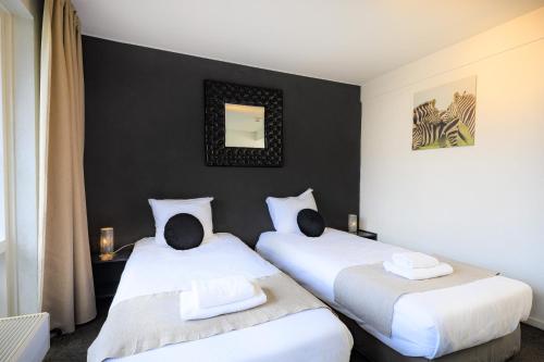 twee bedden in een kamer met zwarte muren bij Hotel Berg en Bos in Apeldoorn