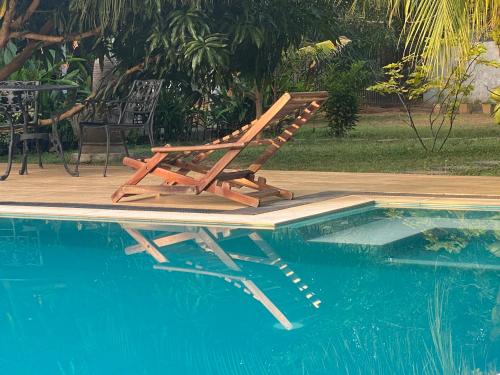 a wooden lounge chair sitting next to a swimming pool at Sapphire Garden Hotel in Habarana