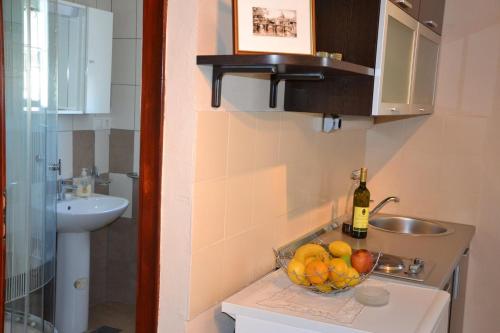 bagno con lavandino e cesto di frutta di Apartments Kodzoman a Brodarica