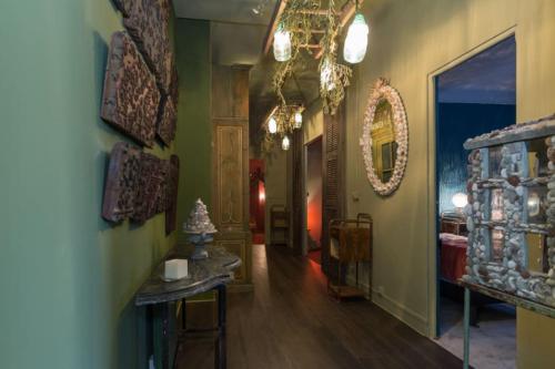 un couloir avec des murs verts et un lustre dans l'établissement Une pause en Provence au Village des antiquaires de la Gare, à LʼIsle-sur-la-Sorgue