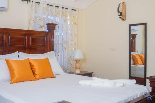 a bedroom with a bed with orange pillows and a mirror at Charming refuge at Colbeck Manor in Old Harbour