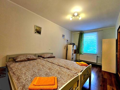 a bedroom with a large bed with an orange blanket at Apartment Hotel Rubini in Ventspils
