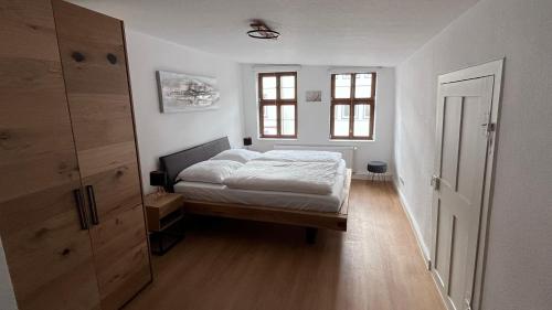 a white bedroom with a bed and two windows at Altstadt Oase Fulda in Fulda