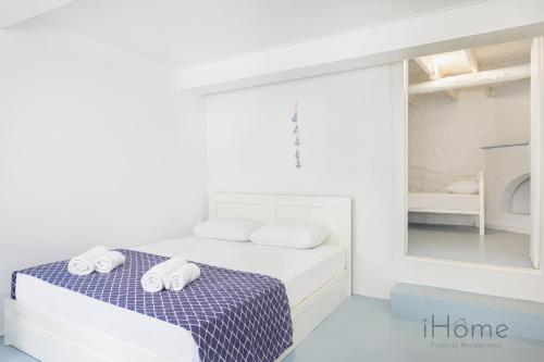 um quarto branco com uma cama com toalhas em Kokkari's Destiny - at the heart of the City Center em Kokkari