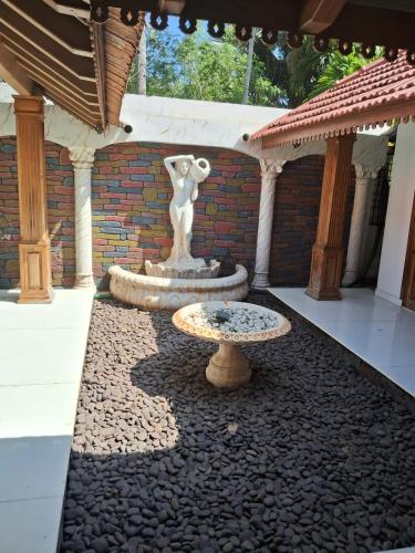 a fountain with a statue in the middle of a courtyard at Jc Pool Villa in Kollam