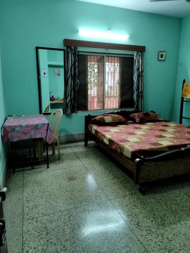 a bedroom with a bed and a table and a window at Aasiyana in Bhubaneshwar