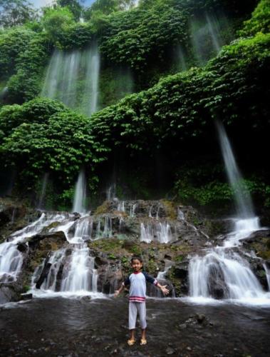 a young boy standing in front of a waterfall at Bujak Permai Villa Matahari Lombok NTB in Praya