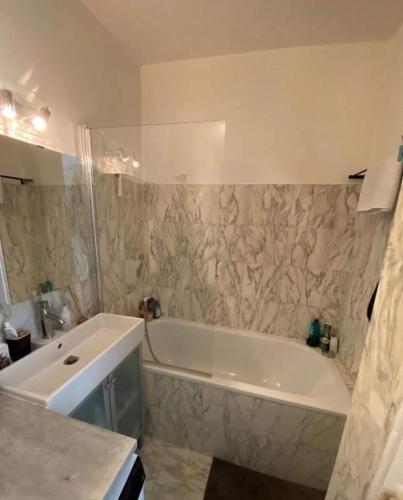 une salle de bain avec une baignoire blanche et un lavabo dans l'établissement Cosy apartment in Levallois, à Levallois-Perret