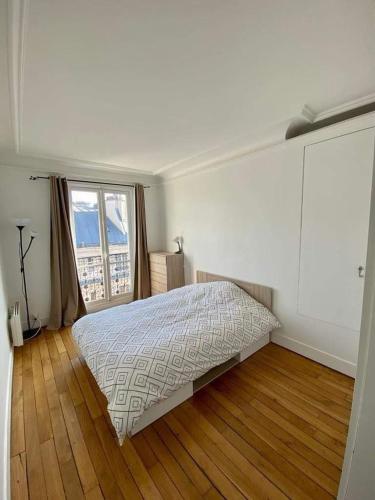 une chambre avec un lit et une grande fenêtre dans l'établissement Cosy apartment in Levallois, à Levallois-Perret