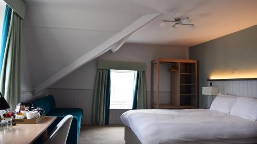 a hotel room with a bed and a desk and a window at Trearddur Bay Hotel in Trearddur