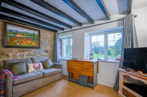 a living room with a couch and a tv at Cosy cottage in rural Culmington, Ludlow in Culmington