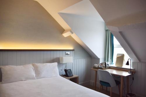a bedroom with a bed and a desk and a window at Trearddur Bay Hotel in Trearddur